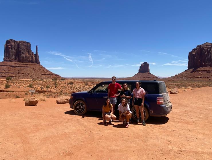 Cinq personnes devant une voiture dans un désert américain